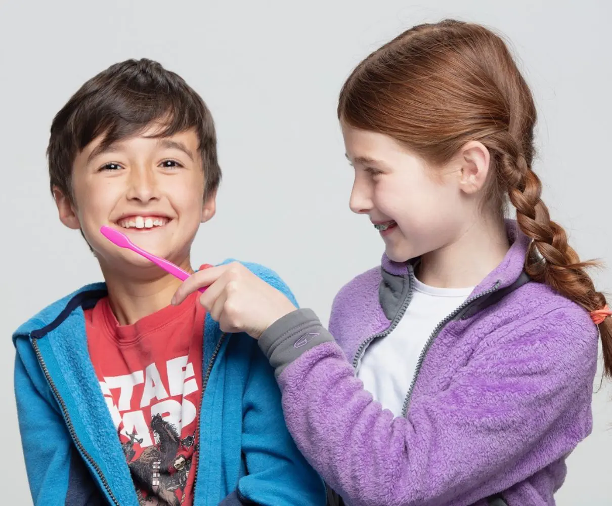 Sibling showing brother how to brush teeth